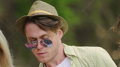Young confident man in hat and sunglasses showing funky dance moves at party