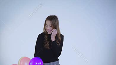 Surprised girl catches balloons and plays with smile on face