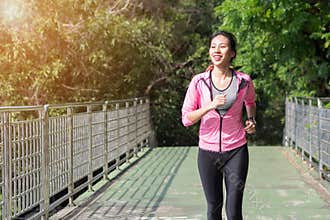 Young asian woman running on sidewalk in morning.
