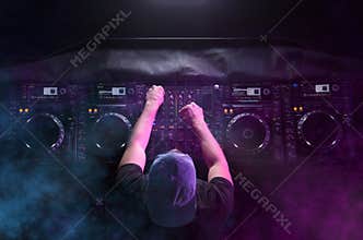 Charismatic disc jockey at the turntable. DJ plays on the best, famous CD players at nightclub during party. EDM, party concept.