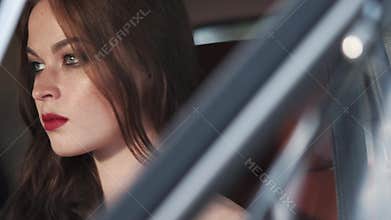 Face of pretty girl with steady gaze, sitting behind a wheel of a car