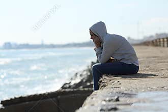 Sad teenager girl alone on the beach