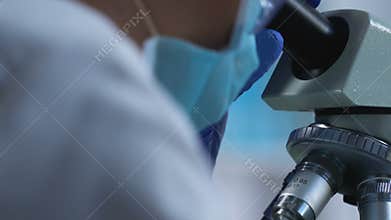 Laboratory worker carefully examining sample under microscope, medical research