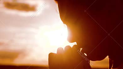 The girl prays. Girl folded her hands in prayer silhouette at sunset. slow motion video. Girl folded her lifestyle hands