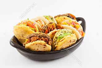 Arepas with assorted fillings served in a black ceramic dish