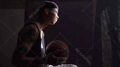 African basketball player sitting and playing with ball, waiting to go to playground for championnat