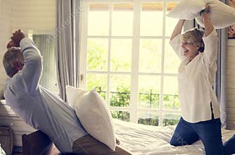 An elderly couple in pillow fight