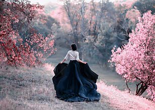 Princess in a vintage dress escapes. Walk through the picturesque autumn hills at sunset in pink tones. A long train of