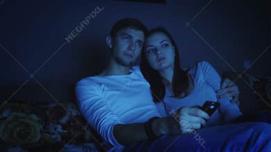 Couple watching television program in dark room