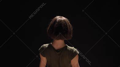 Young charming girl is dancing with hands, watching at camera, black background, ballet concept, movement concept