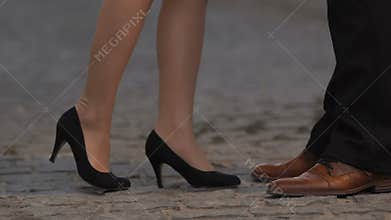 Woman in high heels approaching and kissing boyfriend, outdoor, legs closeup