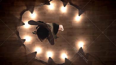 Silhouette of young girl ballerina is dancing on wooden floor, flexure, lights around, ballet concept, movement concept
