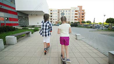 Children learn to ride scooter on sunny summer day. Kids play outdoors with scooters. Active leisure and outdoor sport