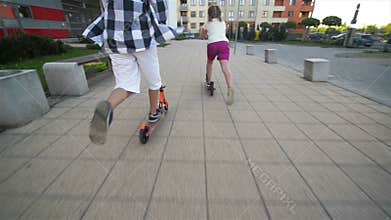 Children learn to ride scooter on sunny summer day. Kids play outdoors with scooters. active leisure and outdoor sport
