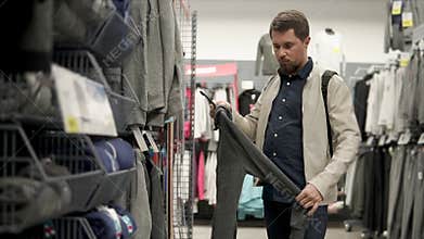 Buyer man is watching a grey hoody in a shop with sport clothes