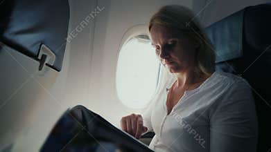 A young woman is reading a magazine in the cockpit of an airplane. Comfort and entertainment in the journey
