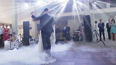 Attractive bride and handsome groom are dancing their first dance in the luxury restaurant hall.