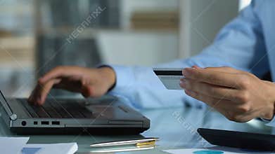 Man making online payment on computer, using card for internet banking services