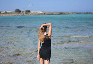 The woman in her slip is entering the transparent water of the sea