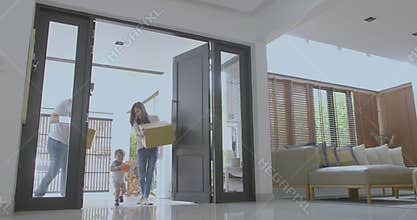 Happy family with kids holding boxes entering new modern house