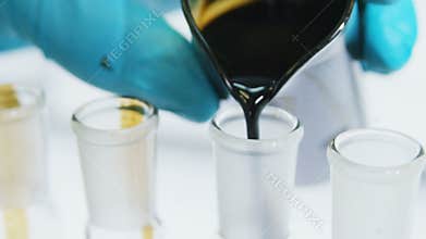 Closeup scientist hand fills tube with raw oil to test