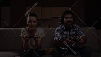 Nice view of couple playing gme together. They hold joystick and use it. They try to play as best as possible. Game is