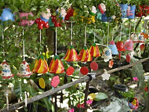 Colorful ceramic wind chimes with natural environment in organic orchid farm with small plants and cartoon decoration.