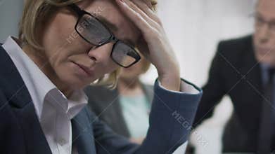 Female office worker upset at conference, feels headache, boss angry about fail