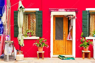 Red house with flowers and plants. Colorful house in Burano island near Venice, Italy