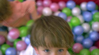 Happy preschool children having fun and playing in multi coloured ball pool. Nursery school