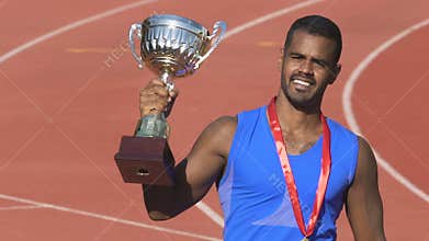Courageous sportsman kissing trophy cup, celebrating triumph and recognition