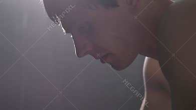 Extreme close shot of sweaty shirtless boxer, drops of water on his face macro