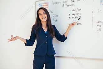 Teacher explaining differences between American and British spelling writing on whiteboard English language school