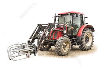 Tractor with hydraulic lift for carrying bales of hay and silage.