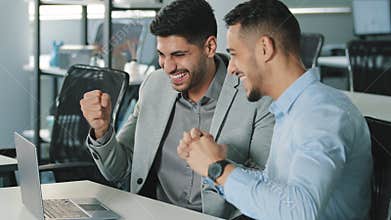 Two happy successful businessmen discussing company development strategy at brainstorming meeting in office. Smiling