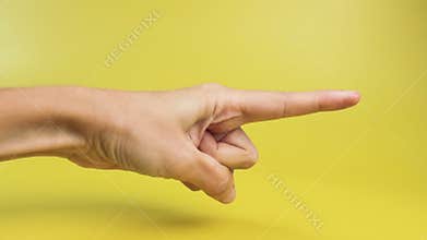 Woman hand with the index finger pointing to the side close-up on a yellow background. Advertising concept, announcements