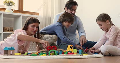 Preteen brother sister build block city on floor with parents