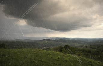 Landscape with rain and dramatic clouds over hills