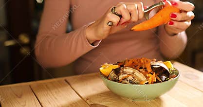 Women scraps peels carrots vegetable peeling, throws in compost bucket, organic composting