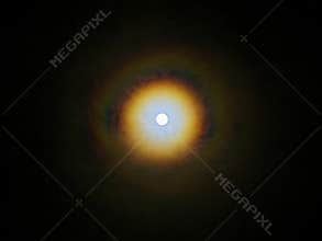 Bright full moon with lunar corona in dark night sky