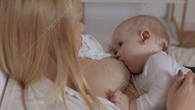 Baby boy drinking milk from mother breast. Concept of breastfeeding, maternity and child healthcare. Young woman feeding