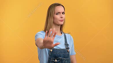 Portrait frowning young blonde woman in denim overalls shaking hand no not forbiddance gesture
