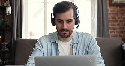 Focused male in wireless earphones use laptop at home office