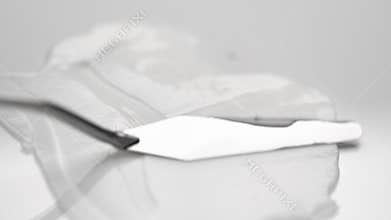 Spreading soft cream over white surface with metal spatula