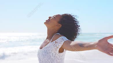 Carefree smiling black woman at beach outstretching arms