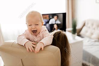 Young woman working at desk at home with computer holding crying tired infant baby holding business meeting at home