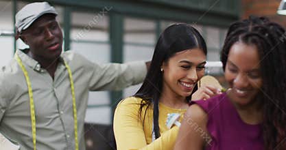 Happy diverse fashion designers wearing tape measures trying on clothes at office