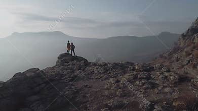 Two hikers stands on cliff in mountains