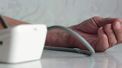 Elderly man measures blood pressure. Close-up of a pensioner`s hand measuring blood pressure while at home. Taking care of your he