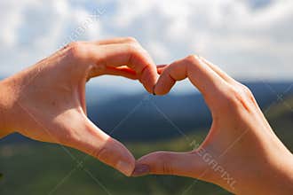 The couple folded their hearts with their hands. Beautiful mountains